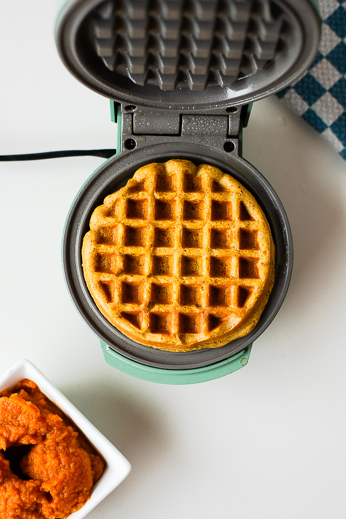 Pumpkin protein waffle cooking in a waffle iron until golden brown