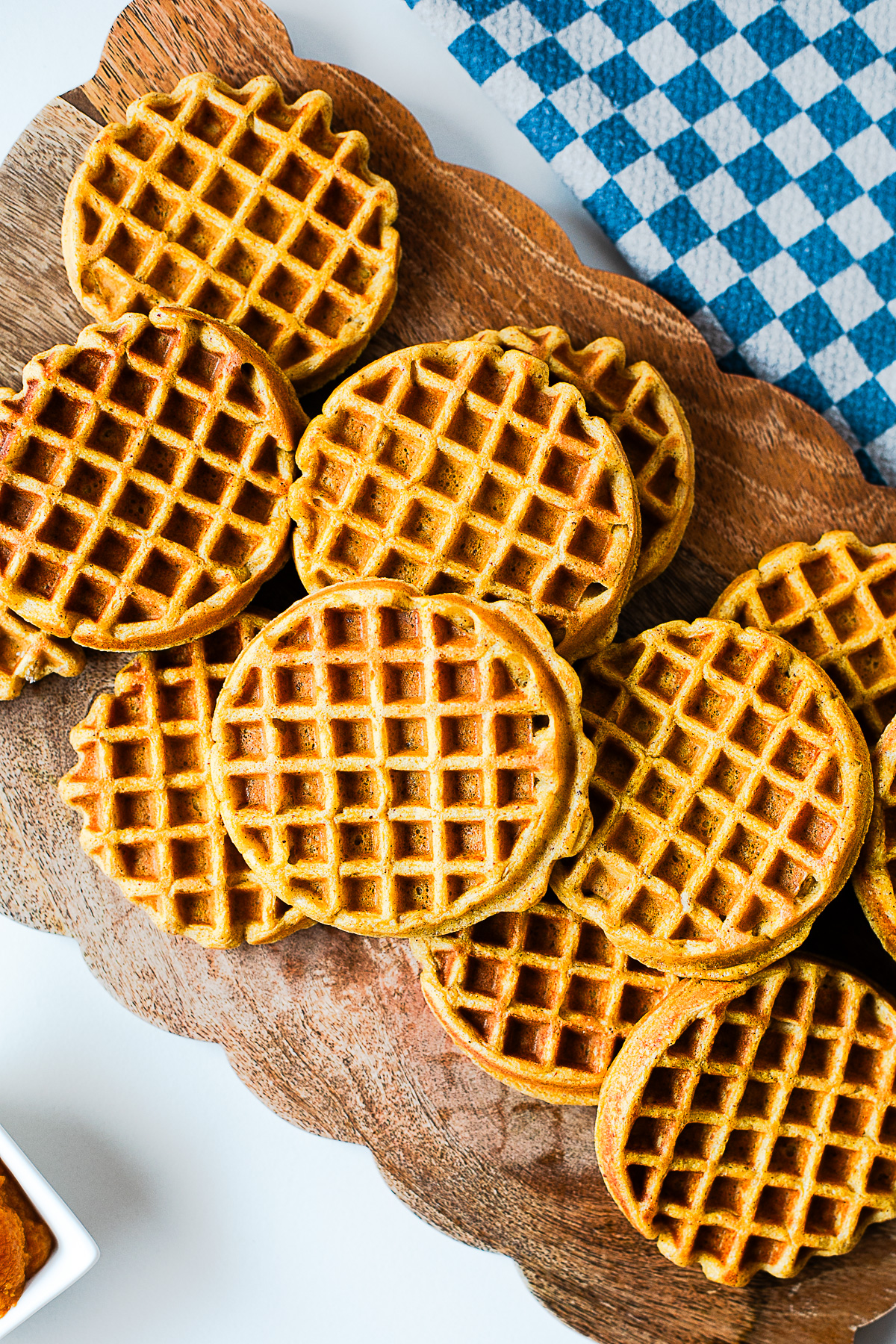 Batch of pumpkin protein waffles ready for meal prep on a wooden board