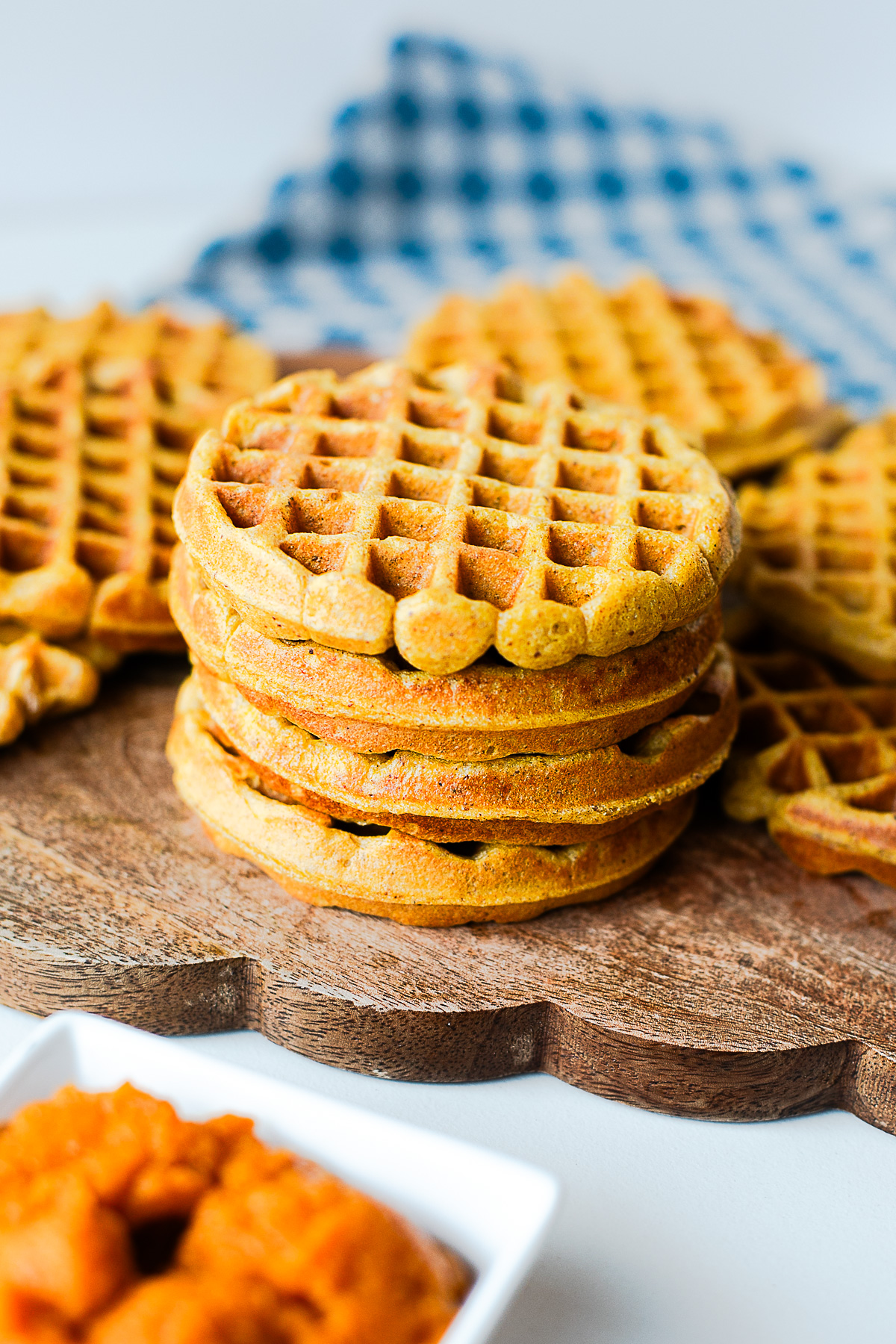 Stack of healthy pumpkin waffles on a wooden board